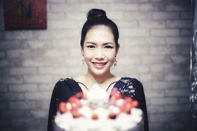 Portrait of smiling young woman against wall