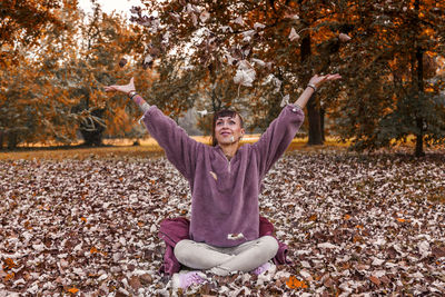 Happy man sitting on autumn leaves in park