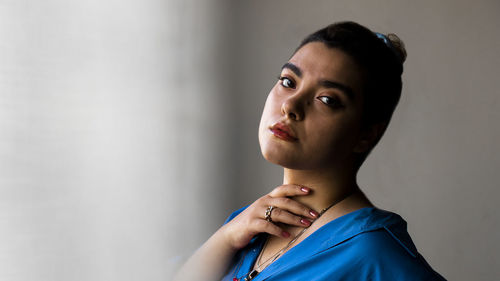 Portrait of young woman standing against wall