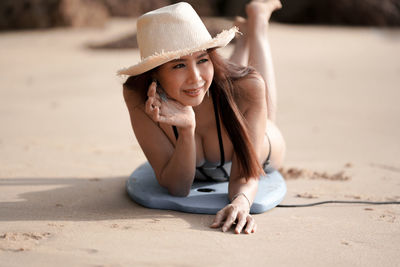 Portrait of young woman sitting on sand at beach