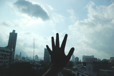 Silhouette hand against sky in city