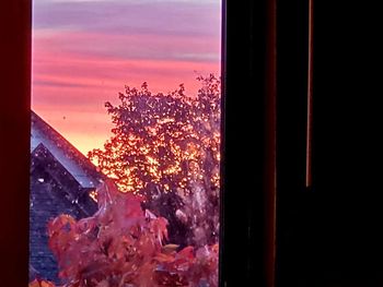 Close-up of glass window against orange sky