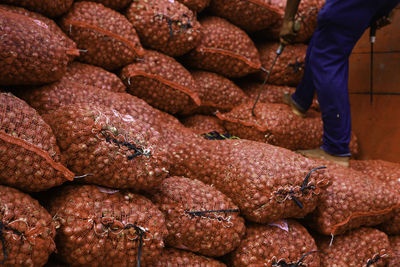 Low section of man standing by sacks with onions at market
