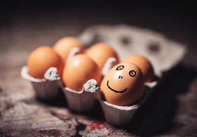 Close-up of smiley face on brown egg in carton