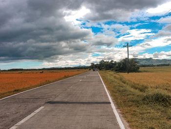 Road amidst field against sky