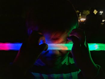 Midsection of man holding illuminated lighting equipment at night