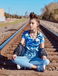 Young woman sitting on railroad track