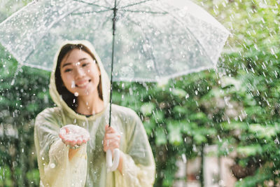 Woman holding wet while standing in rain during rainy season