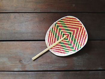 Directly above shot of multi colored hand fan on wooden table