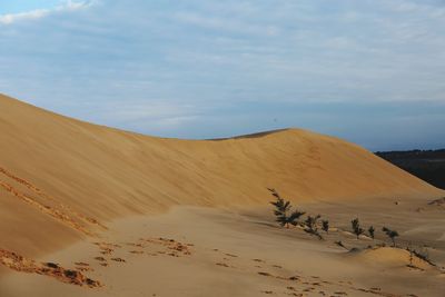 Scenic view of desert against cloudy sky