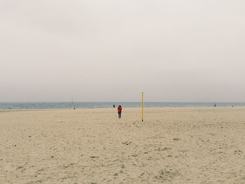 People playing on beach against clear sky