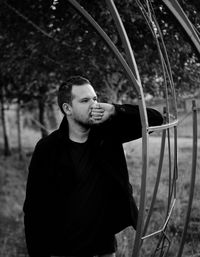Young man looking away while standing on land