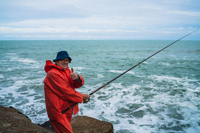 Man fishing in sea against sky