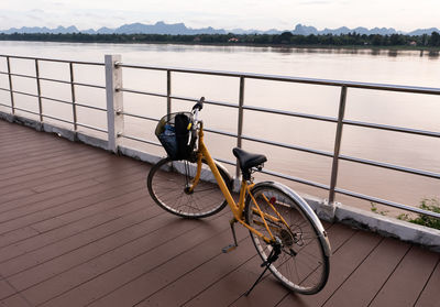 Bicycle parked by railing by lake