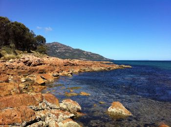 Scenic view of sea and mountains against clear blue sky