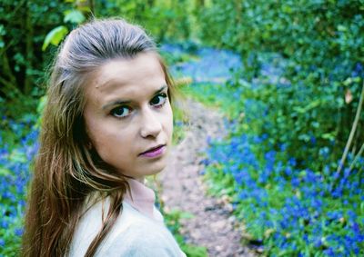 Portrait of young woman by plants on field