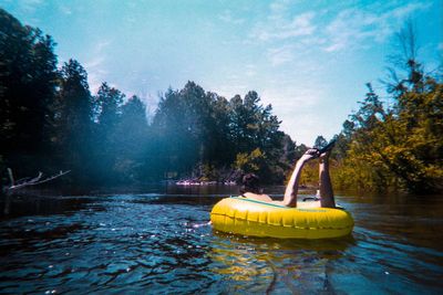 Yellow floating on river against sky
