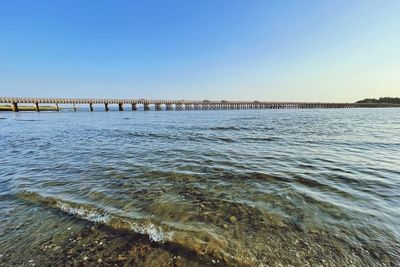 Bridge over sea against clear sky