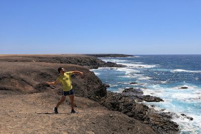 Man throwing standing in sea against clear sky