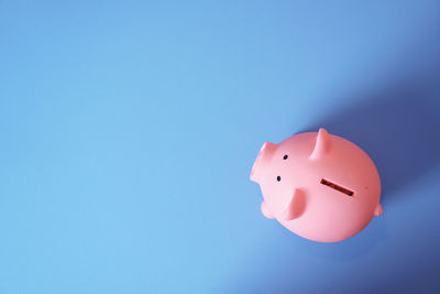 High angle view of pink piggy bank on blue background