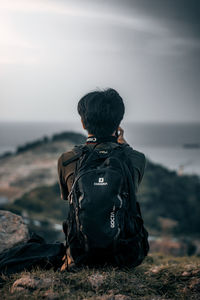 Rear view of man looking at sea against sky