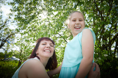 Portrait of smiling young woman standing against trees