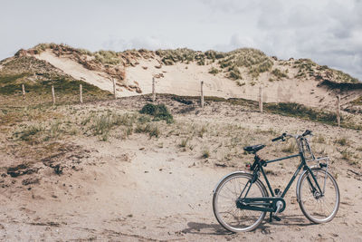 Bicycle on barren landscape against the sky