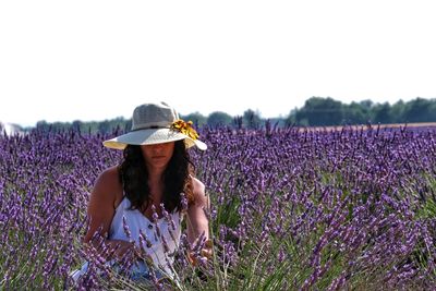 Woman wearing hat amidst lavender flowers