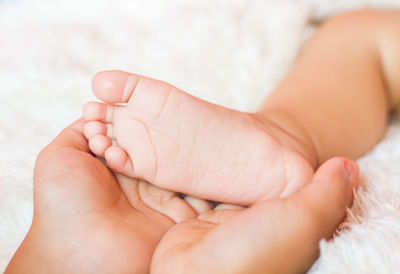 Cropped hand of woman holding baby foot at home