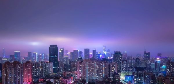 Illuminated city skyline against sky at night
