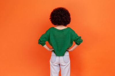 Rear view of boy standing against yellow background