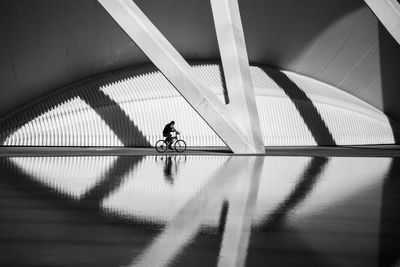 Reflection of man cycling against built structure