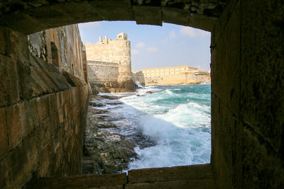 Buildings by sea against sky