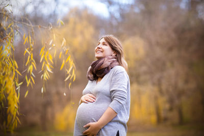 Smiling young woman standing against blurred background