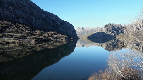 Scenic view of lake and mountains against clear blue sky