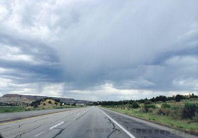 Country road against cloudy sky