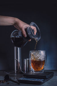 Close-up of hand pouring coffee in glass