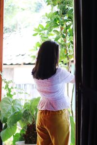 Rear view of woman standing against window