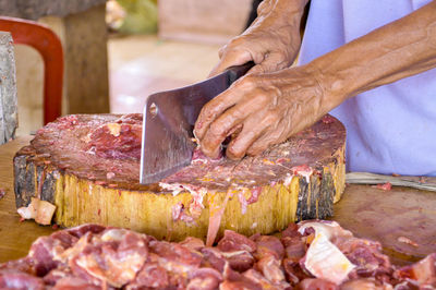 Midsection of man cutting meat on cutting board