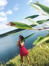 Woman hands covering mouth while standing on field against sky