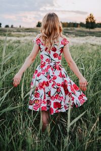 Rear view of woman walking amidst plants against sky