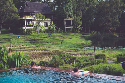 Man and woman swimming in pool by farm