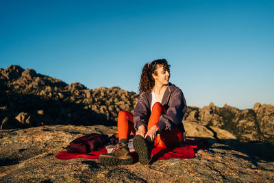 Man sitting on rock against clear sky