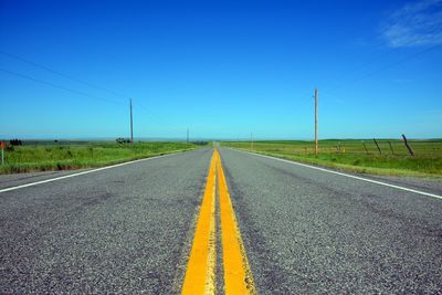 Surface level of road against clear blue sky