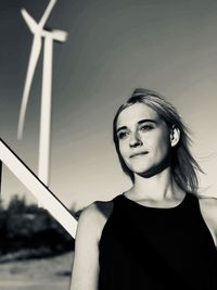 Thoughtful woman standing against windmills