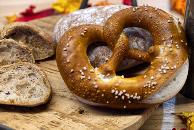 A composition of cereal bread and pretzels on a wooden cutting board