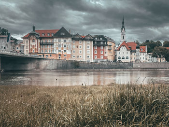 Buildings by river against sky