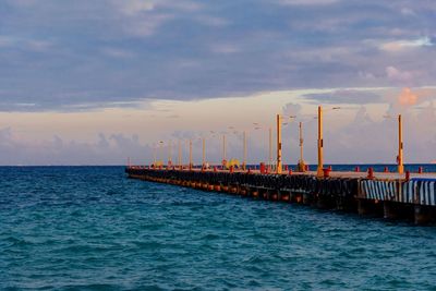 Pier over sea against sky during sunset