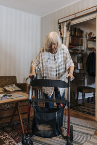 Senior woman walking at home using mobility walker