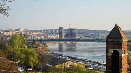 Bridge over river in city against sky